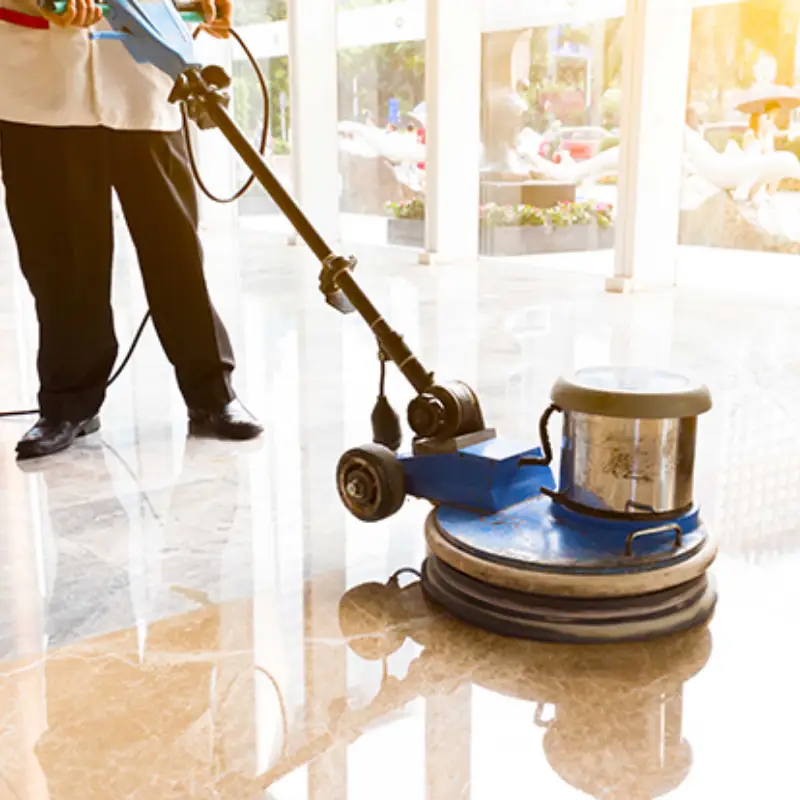 Técnico uniformado operando pulidora industrial sobre piso de losetas brillantes en lobby comercial iluminado en Campeche