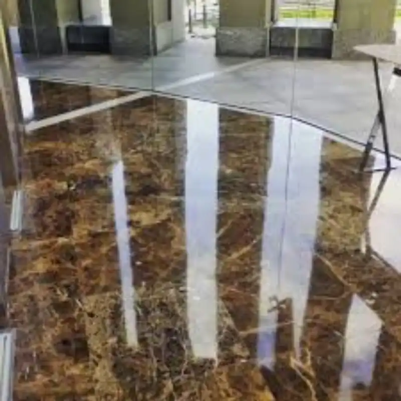 Diamantado de pisos en mármol oscuro con acabado espejo en complejo corporativo de San Pedro Garza García, Nuevo León — Pulistone Lobby de complejo corporativo de uso mixto en San Pedro Garza García, Nuevo León, con piso de mármol café imperial diamantado a espejo por Pulistone, reflejando columnas y estructura arquitectónica tras proceso de desbastado de pisos de cemento y acabado antideslizante de alta durabilidad