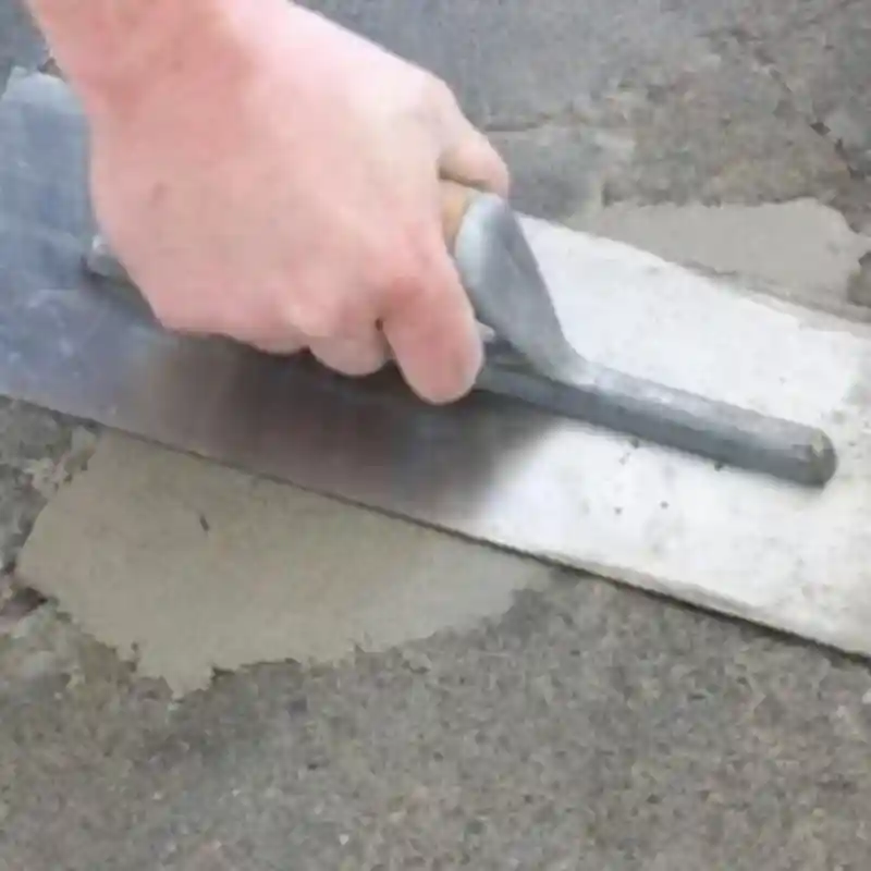 Retapado profesional de grietas y juntas en piso de concreto en Monterrey, Nuevo León — Pulistone Técnico de Pulistone aplicando mezcla de alta adherencia con llana metálica para retapado de grietas y juntas abiertas en piso de concreto deteriorado en propiedad residencial de Monterrey, Nuevo León, restaurando continuidad visual y estructural